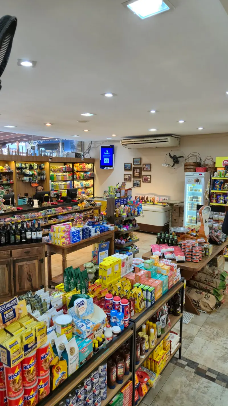 Gôndolas de mercearia com produtos variados e salão ao fundo