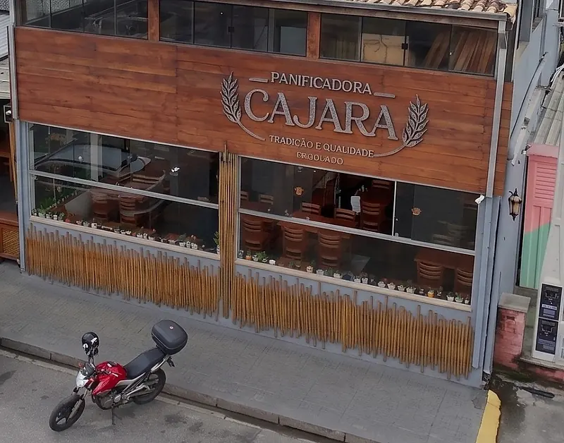 Fachada da Panificadora Cajara com o letreiro em madeira e o deck de bambu